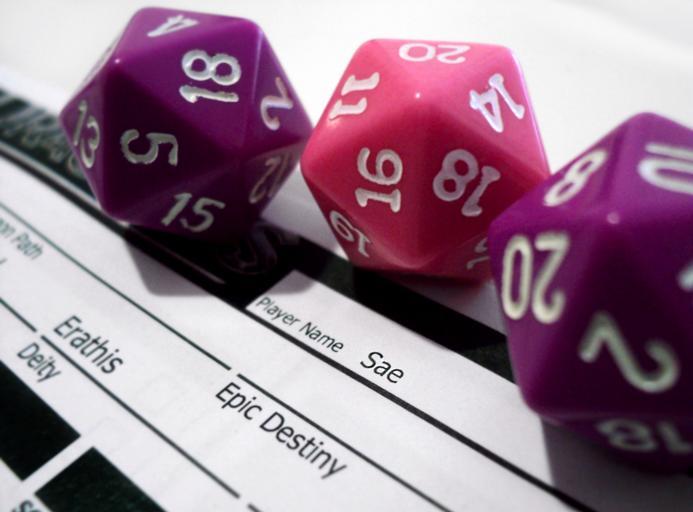 Purple and pink twenty sided dice on a character sheet. 